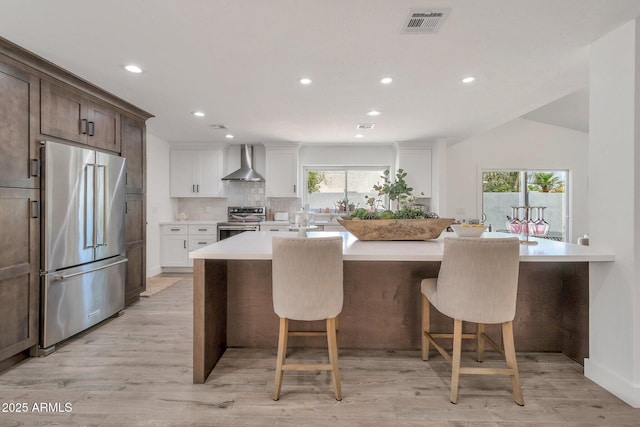 8719 E San Marino Dr, Scottsdale, AZ 85258 - kitchen with light countertops, wall chimney exhaust hood, appliances with stainless steel finishes, visible vents, and recessed lighting