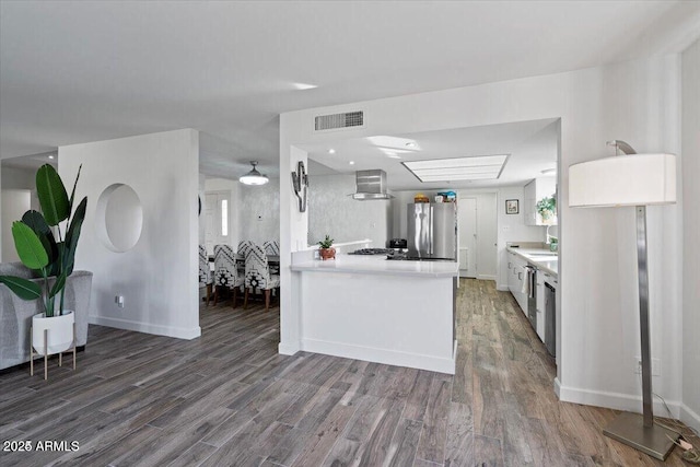 kitchen with light countertops, wood finished floors, visible vents, and freestanding refrigerator