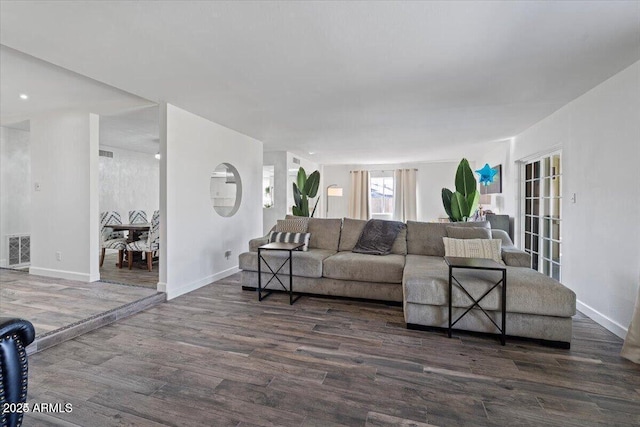 living room with visible vents, baseboards, and wood finished floors