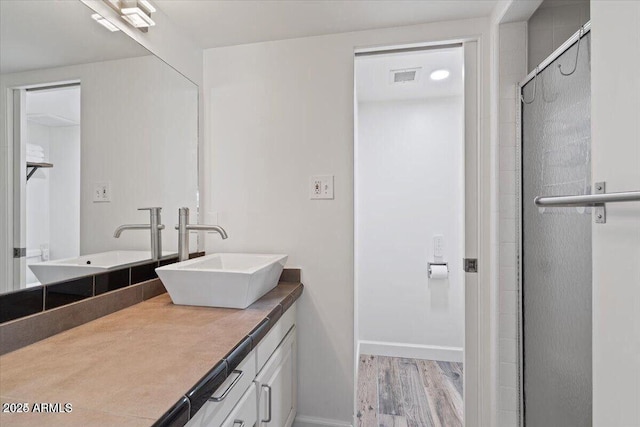 bathroom with visible vents, a shower stall, baseboards, wood finished floors, and vanity