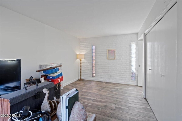 office with brick wall, baseboards, and wood finished floors