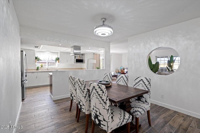 dining space with light wood-style flooring, a healthy amount of sunlight, and baseboards