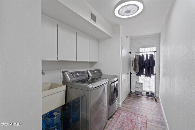 laundry area featuring visible vents, baseboards, light wood-type flooring, cabinet space, and independent washer and dryer