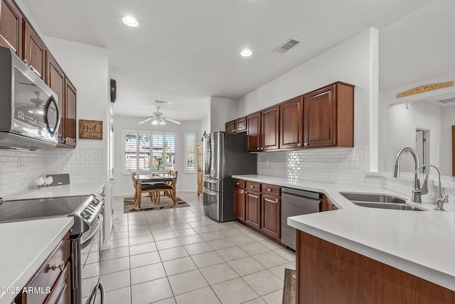 kitchen with ceiling fan, backsplash, sink, light tile patterned flooring, and stainless steel appliances