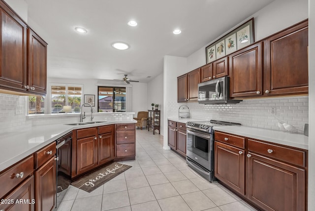 kitchen with ceiling fan, kitchen peninsula, appliances with stainless steel finishes, and sink