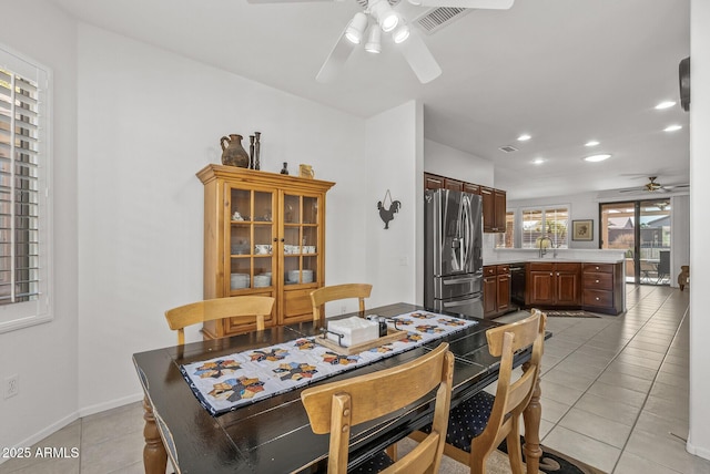 tiled dining space with ceiling fan and sink