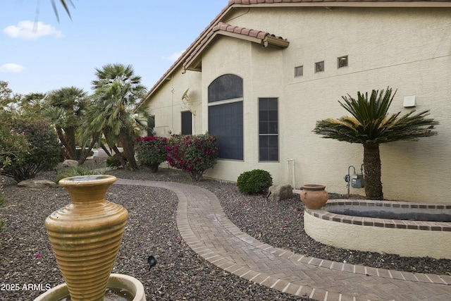 view of side of property featuring stucco siding and a tile roof