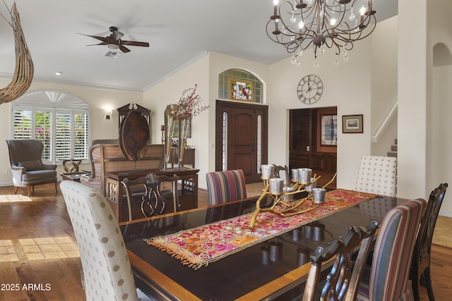 dining space featuring stairs, crown molding, ceiling fan with notable chandelier, and wood finished floors