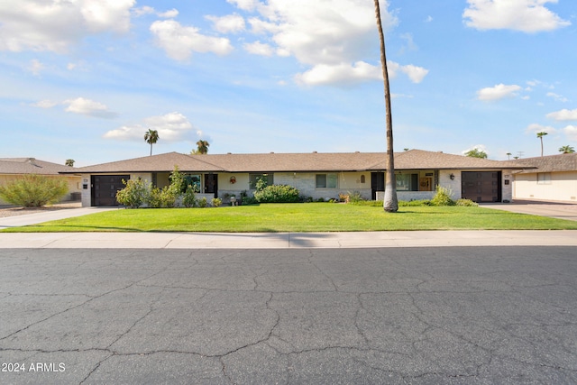 ranch-style house featuring a garage, concrete driveway, and a front yard