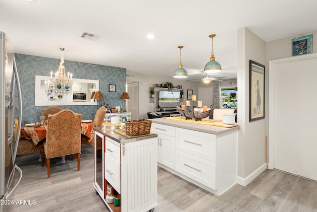 kitchen with an accent wall, visible vents, light wood-style floors, freestanding refrigerator, and wallpapered walls