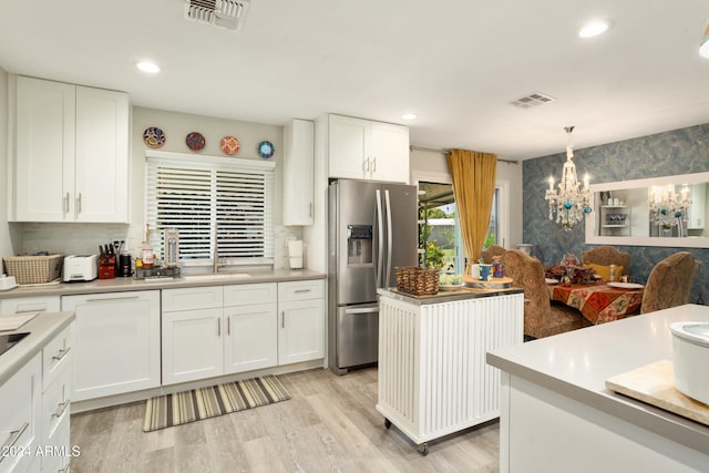 kitchen featuring stainless steel refrigerator with ice dispenser, a center island, decorative light fixtures, and white cabinetry