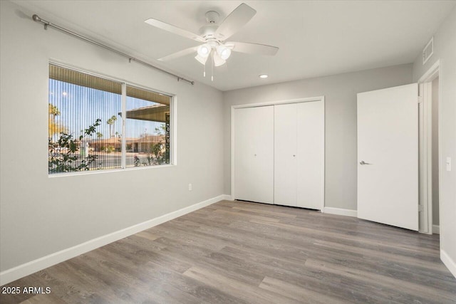 unfurnished bedroom featuring baseboards, a closet, visible vents, and wood finished floors