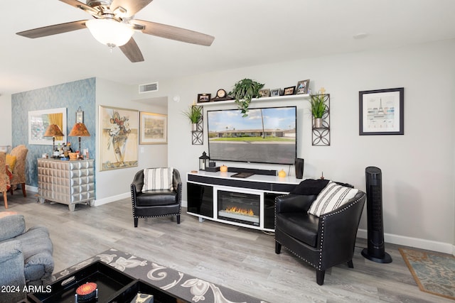 living room featuring a ceiling fan, visible vents, baseboards, and wood finished floors