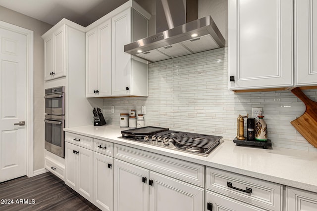 kitchen featuring white cabinetry, appliances with stainless steel finishes, dark hardwood / wood-style floors, decorative backsplash, and wall chimney exhaust hood