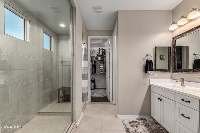 bathroom featuring vanity, tile patterned flooring, and a tile shower