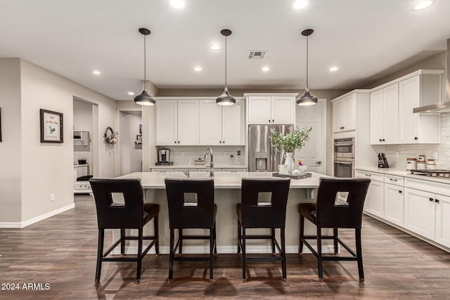 kitchen featuring a kitchen island with sink, appliances with stainless steel finishes, dark hardwood / wood-style floors, and decorative light fixtures