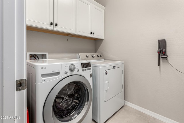 laundry room with cabinets, washing machine and clothes dryer, and light tile patterned floors