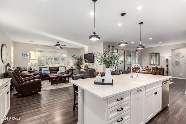 kitchen with white cabinets, a center island with sink, sink, and decorative light fixtures