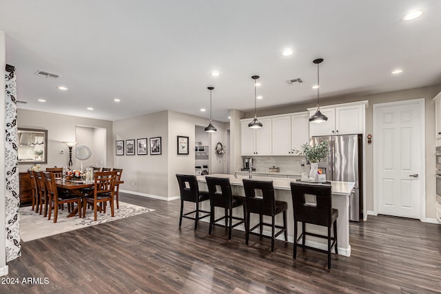 kitchen with hanging light fixtures, dark hardwood / wood-style floors, and an island with sink