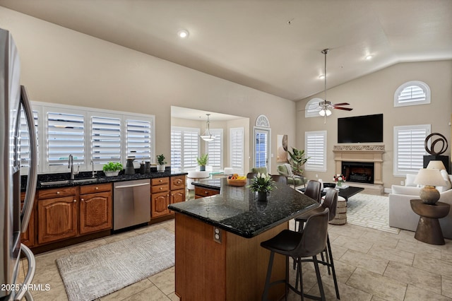 kitchen with appliances with stainless steel finishes, a kitchen island, pendant lighting, vaulted ceiling, and plenty of natural light