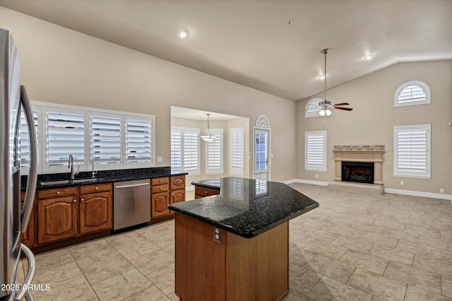 kitchen with a center island, decorative light fixtures, stainless steel appliances, dark stone counters, and vaulted ceiling