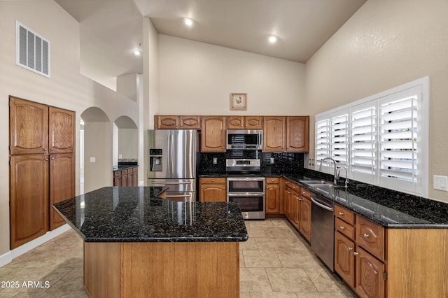 kitchen with high vaulted ceiling, appliances with stainless steel finishes, and a center island