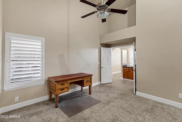 office featuring a towering ceiling and ceiling fan