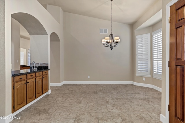 dining area featuring sink, a chandelier, and lofted ceiling