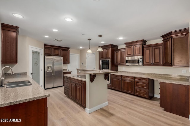 1535 E Kenwood St, Mesa, AZ 85203 - kitchen featuring appliances with stainless steel finishes, a sink, light wood-style flooring, light stone counters, and hanging light fixtures