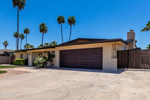 1535 E Kenwood St, Mesa, AZ 85203 - ranch-style house featuring concrete driveway, brick siding, an attached garage, a chimney, and fence