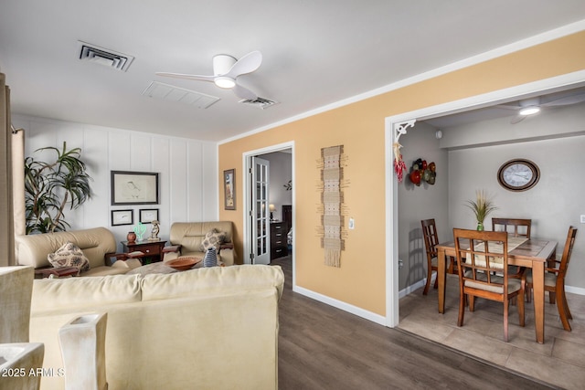 living area featuring baseboards, ceiling fan, visible vents, and crown molding