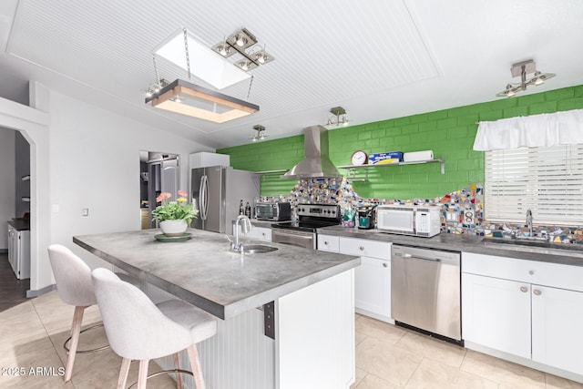 23948 W Jomax Rd, Wittmann, AZ 85361 - kitchen featuring stainless steel appliances, wall chimney exhaust hood, a sink, dark countertops, and vaulted ceiling