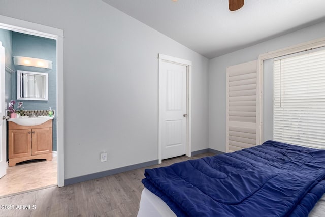 23948 W Jomax Rd, Wittmann, AZ 85361 - bedroom with lofted ceiling, a sink, light wood-type flooring, baseboards, and connected bathroom