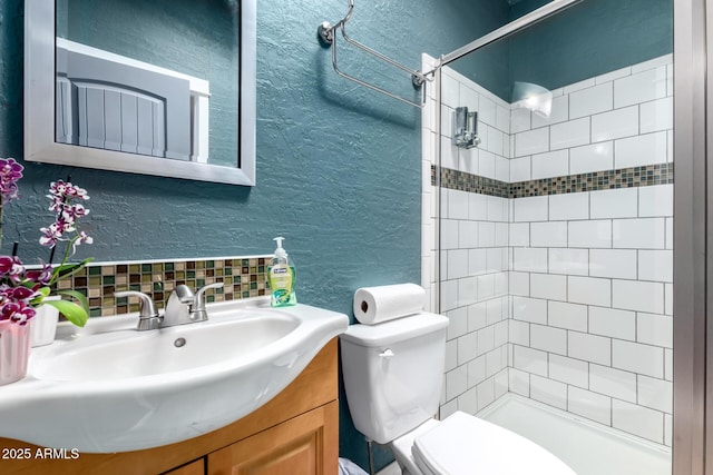 23948 W Jomax Rd, Wittmann, AZ 85361 - bathroom featuring toilet, a tile shower, a textured wall, vanity, and backsplash