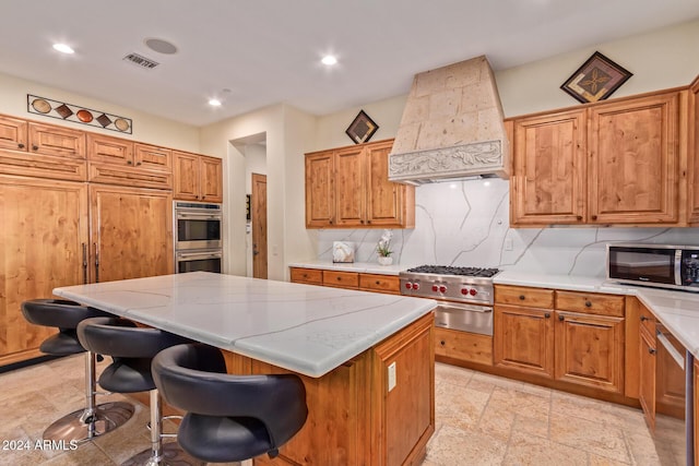 kitchen featuring a breakfast bar area, a kitchen island, custom exhaust hood, and appliances with stainless steel finishes