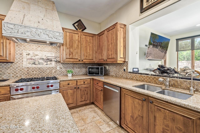 kitchen featuring light stone countertops, sink, tasteful backsplash, custom range hood, and appliances with stainless steel finishes