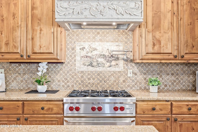 kitchen with tasteful backsplash, light stone counters, and high end range