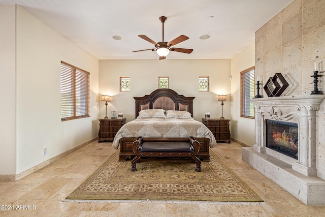 bedroom featuring ceiling fan and a large fireplace