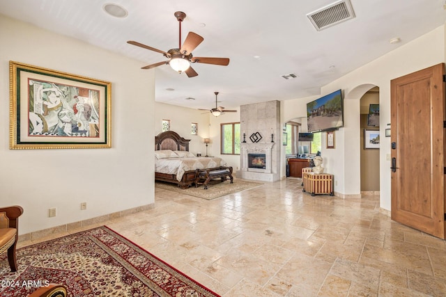 bedroom with a large fireplace and ceiling fan