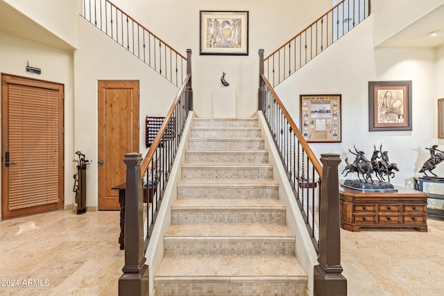 stairway featuring a towering ceiling