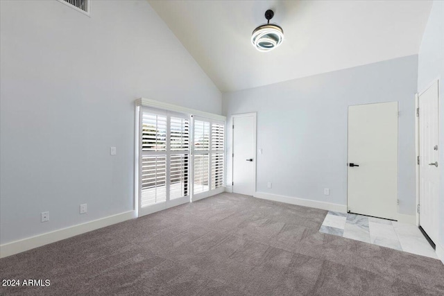 carpeted empty room with high vaulted ceiling