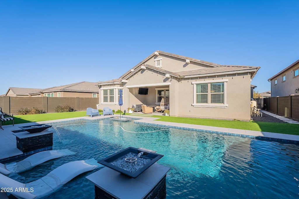 back of house featuring a patio, a lawn, a fenced in pool, pool water feature, and a fire pit