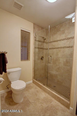 bathroom with tile patterned floors, toilet, and an enclosed shower