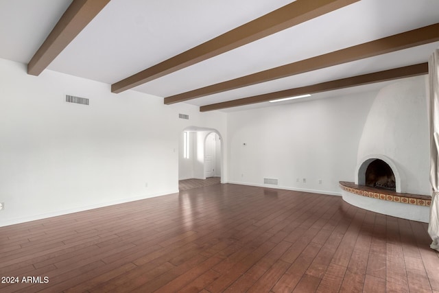 unfurnished living room featuring dark hardwood / wood-style floors, a large fireplace, and beam ceiling