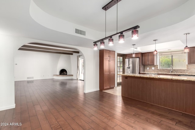 kitchen with pendant lighting, dark wood-type flooring, light stone countertops, tasteful backsplash, and stainless steel fridge with ice dispenser