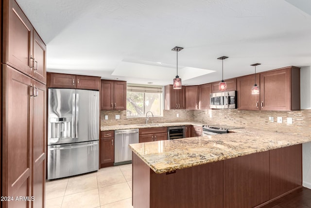 kitchen with sink, kitchen peninsula, hanging light fixtures, and appliances with stainless steel finishes