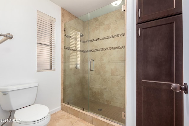 bathroom with toilet, tile patterned floors, and a shower with door