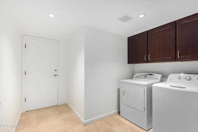 laundry area featuring separate washer and dryer, light tile patterned floors, and cabinets