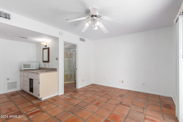 kitchen featuring tile patterned floors, ceiling fan, sink, and white cabinets