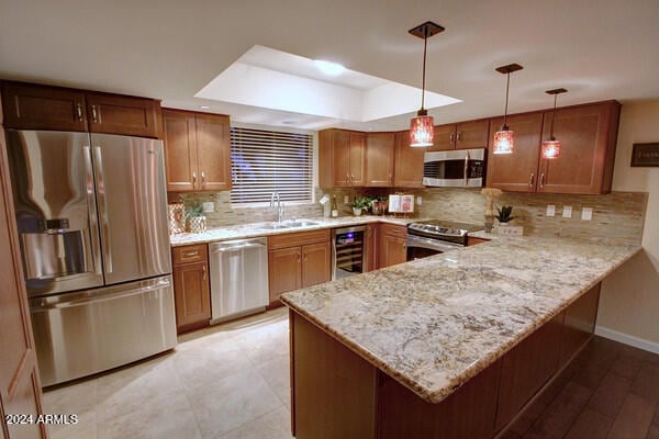 kitchen with sink, hanging light fixtures, wine cooler, kitchen peninsula, and appliances with stainless steel finishes